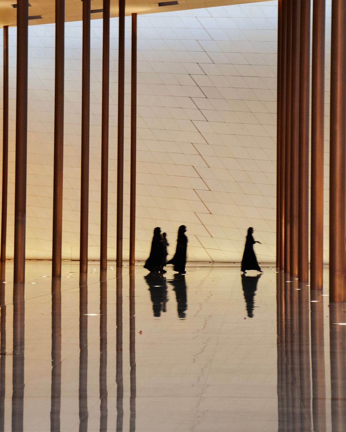 Silhouetted figures walking through a modern colonnade in Manah, Oman